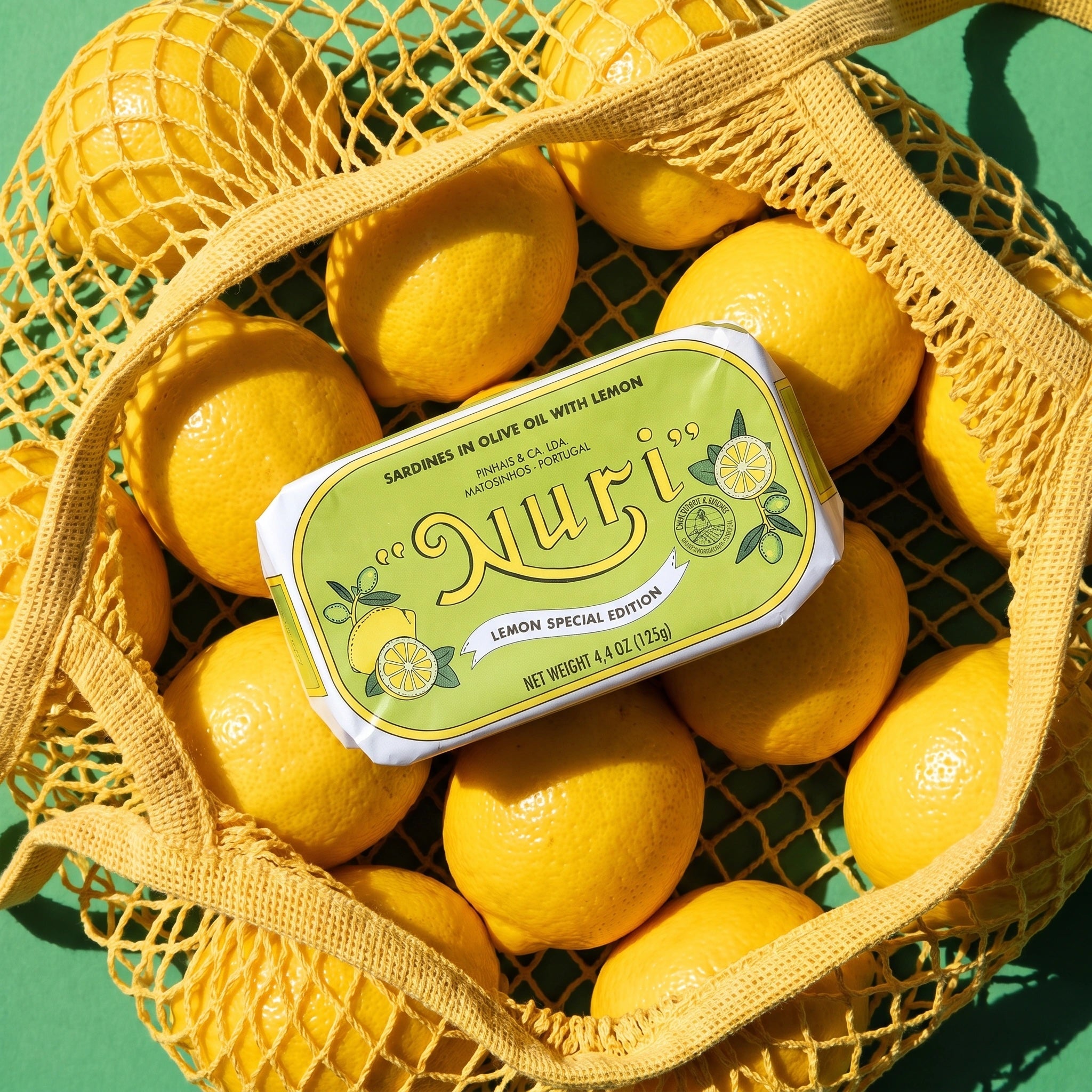 Nuri Sardines in Olive Oil with Lemon surrounded by whole lemons in grocery bag