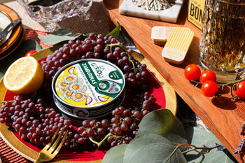 Elegant spread of berries and fruit surrounding a tin of La Curiosa scallops